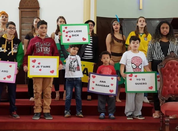 Grupo de jovens e crianças segurando cartazes com os dizeres eu te amo em varios idiomas