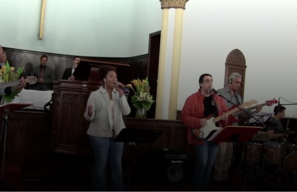 Foto com pessoas cantando e tocando musica em cima do altar