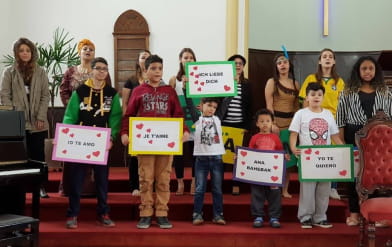 Foto de jovens e crianças segurando cartazes com os dizeres de eu te amo em varios idiomas