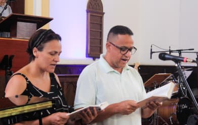 Uma senhora e um senhor lendo a biblia dentro da igreja