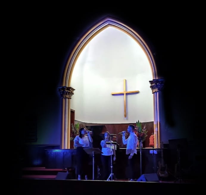 Foto de 3 jovens cantando durante um culto na igreja