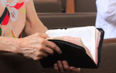Foto das mãos de uma pessoa segurando uma biblia
